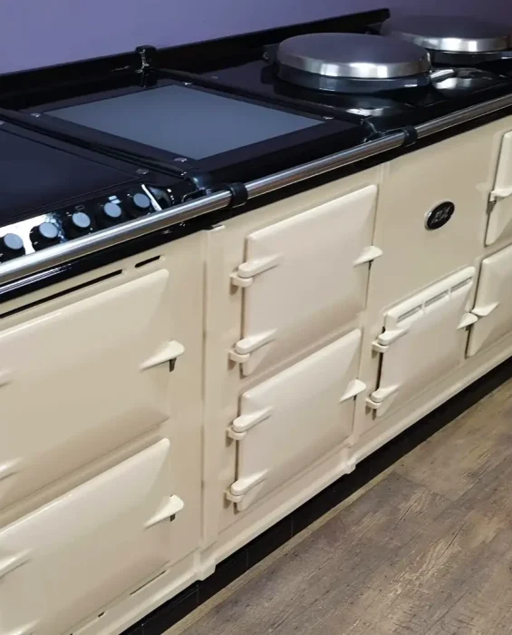 Cream aga cooker with integrated control panel and stainless steel hotplates in a modern kitchen setting. Displayed by John Wray Range Cookers.